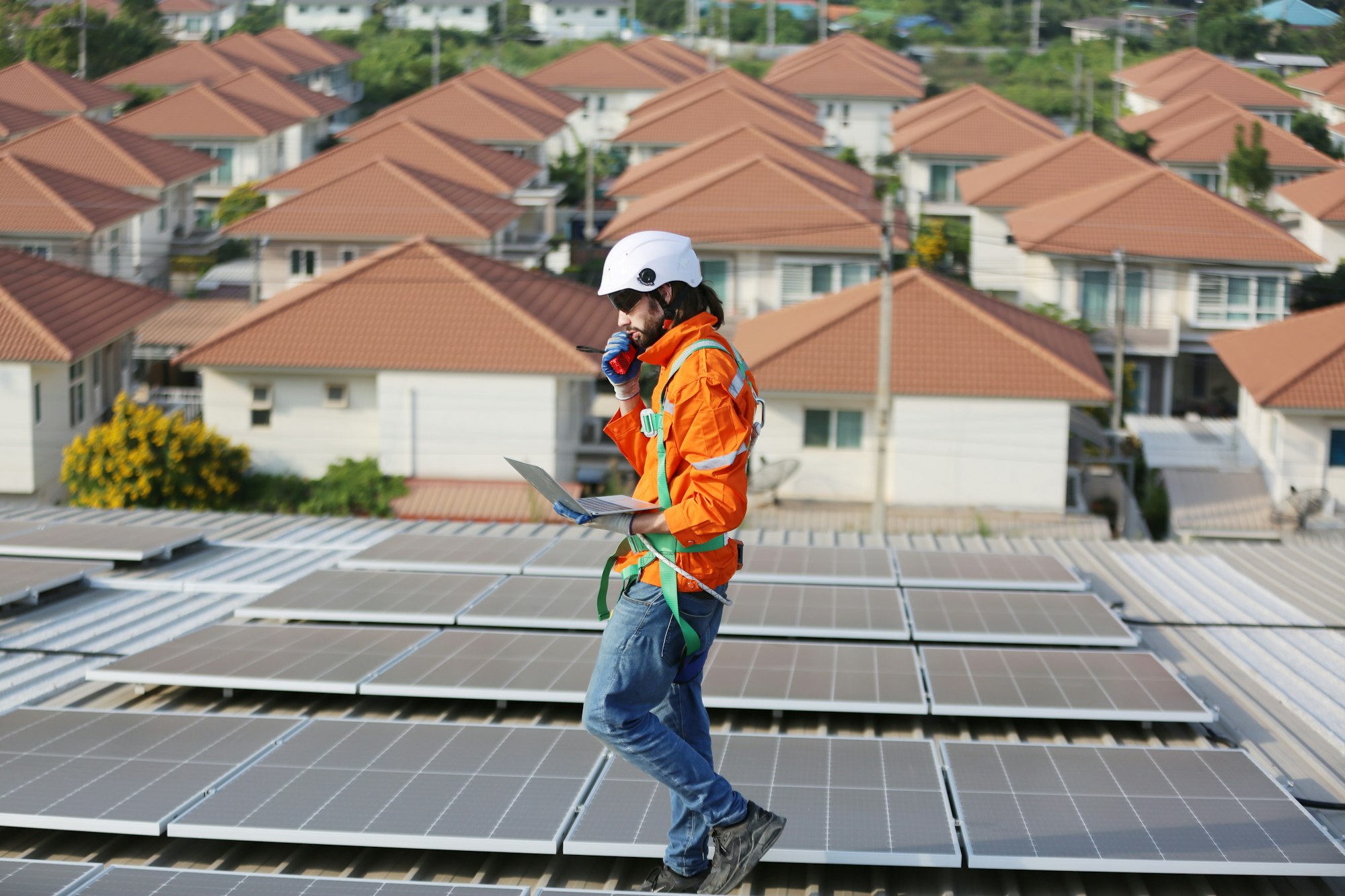 mature male engineers walking along the rows of photovoltaic panels on a rooftop of a solar plant.